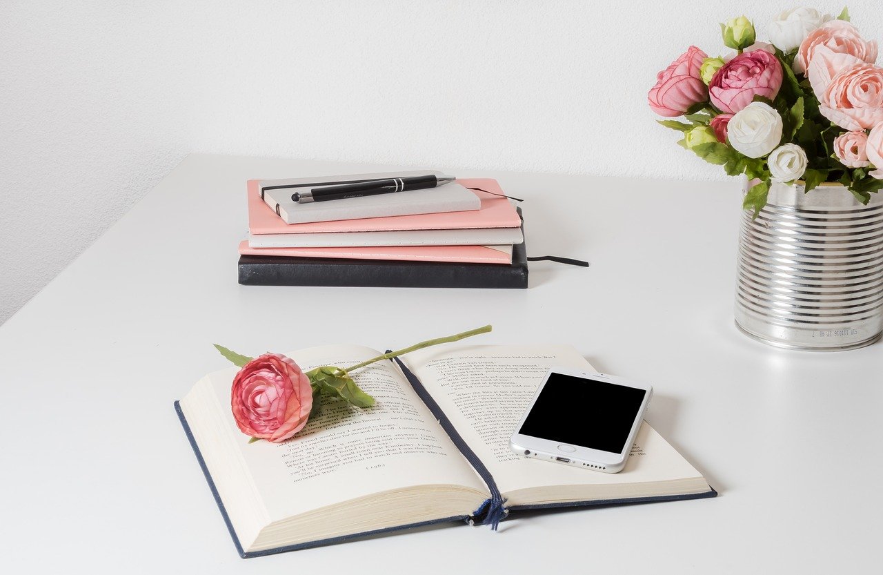 Open book and pink flowers on desktop